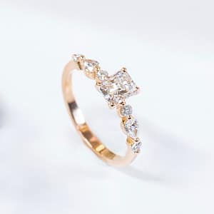 Bague de fiançailles or rouge 18 carats, diamant taille radiant 0,70cts accompagné de diamants tailles brillant et poires 0,31 cts, pour femme, collection La Joaillerie